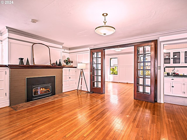 unfurnished living room featuring hardwood / wood-style floors and crown molding