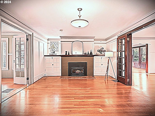 unfurnished living room with french doors, light wood-type flooring, and crown molding