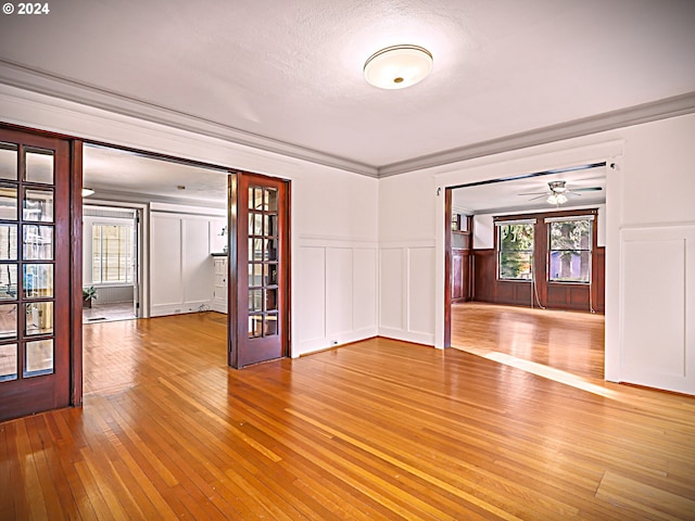 empty room featuring a textured ceiling, light wood-type flooring, plenty of natural light, and ceiling fan