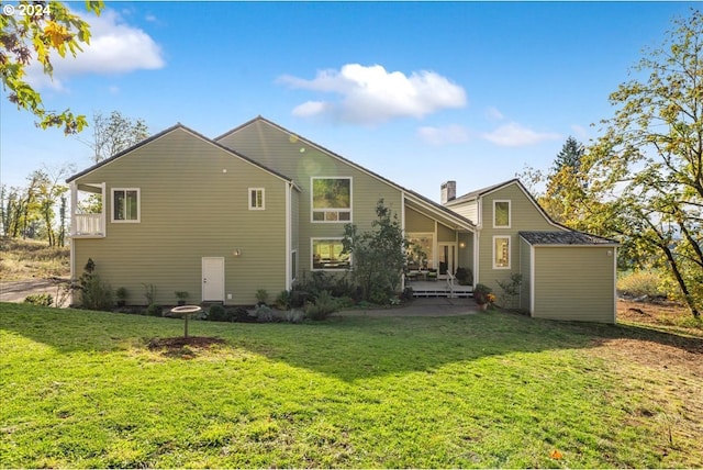 back of house with a storage unit and a lawn