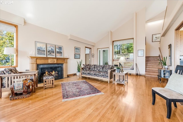 living room featuring a premium fireplace, high vaulted ceiling, wood-type flooring, and plenty of natural light