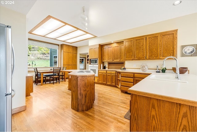 kitchen with sink, light hardwood / wood-style flooring, stainless steel appliances, and a center island