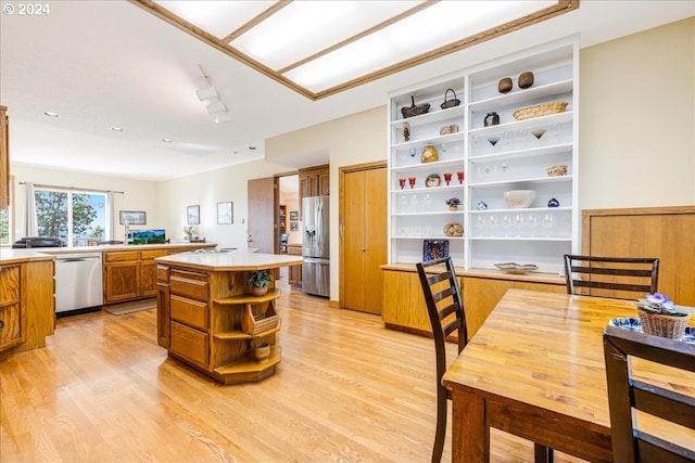 kitchen featuring rail lighting, stainless steel appliances, light hardwood / wood-style floors, and kitchen peninsula