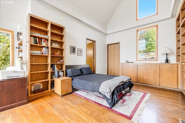 bedroom with high vaulted ceiling, multiple windows, and light wood-type flooring