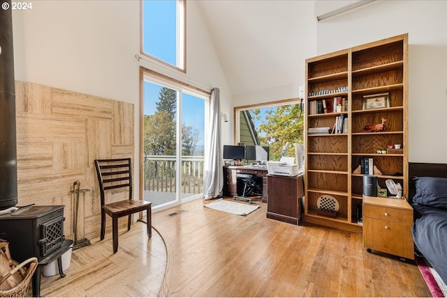 living area featuring light hardwood / wood-style floors, a wood stove, and high vaulted ceiling