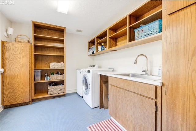 clothes washing area with independent washer and dryer, cabinets, and sink