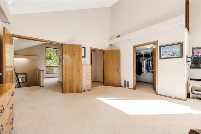 bedroom featuring lofted ceiling, light carpet, a walk in closet, and a closet