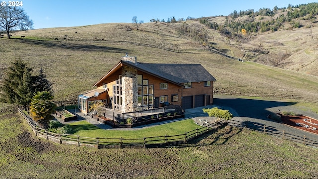 back of house with a lawn, a mountain view, a rural view, and a garage