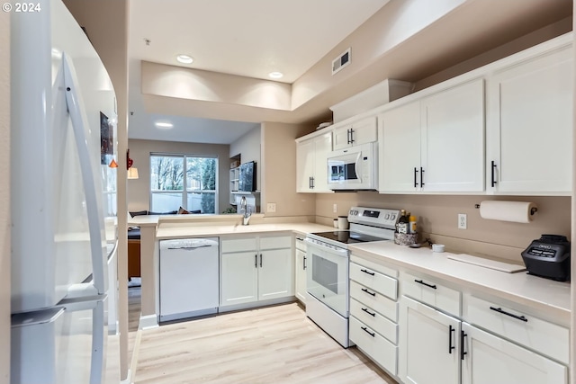 kitchen with kitchen peninsula, light wood-type flooring, white appliances, sink, and white cabinets