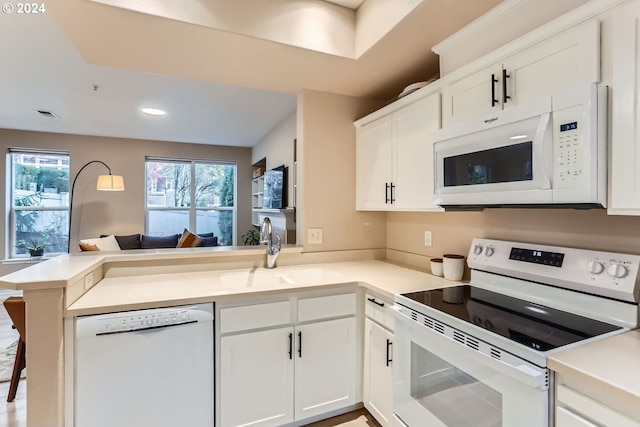 kitchen with white cabinetry, sink, white appliances, and kitchen peninsula