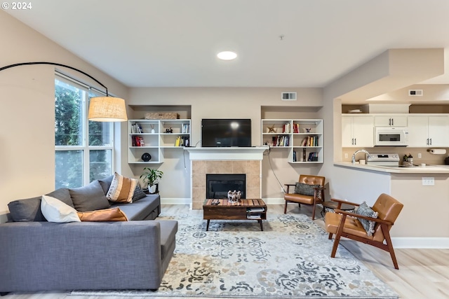 living room featuring a tile fireplace and light hardwood / wood-style flooring