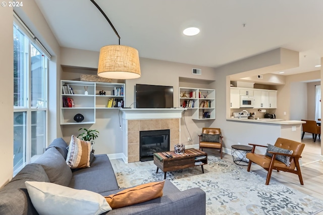 living room featuring a tile fireplace and light wood-type flooring