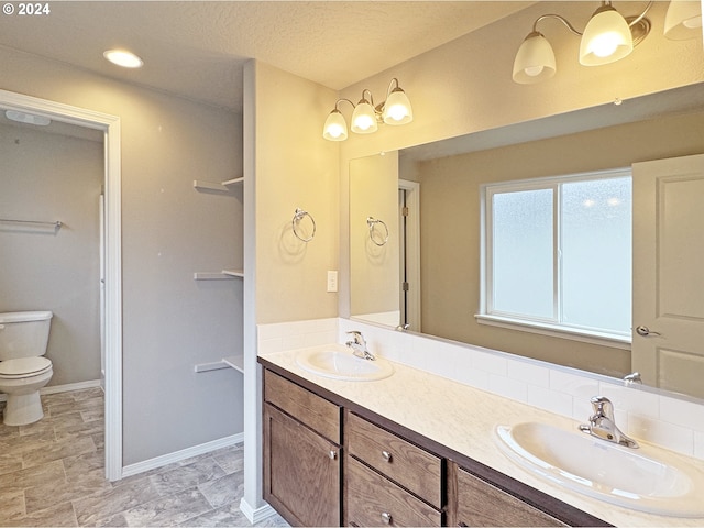 bathroom with vanity, toilet, and a textured ceiling