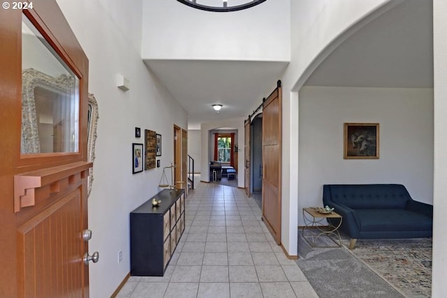 corridor with a barn door and light tile patterned flooring