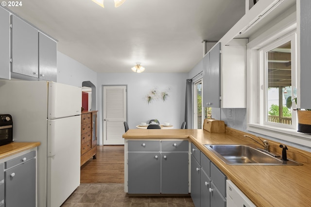 kitchen with white refrigerator, gray cabinetry, sink, and a healthy amount of sunlight