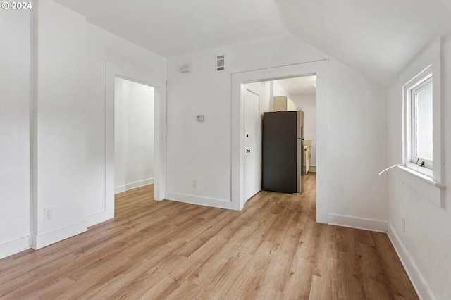 empty room featuring lofted ceiling and light hardwood / wood-style flooring