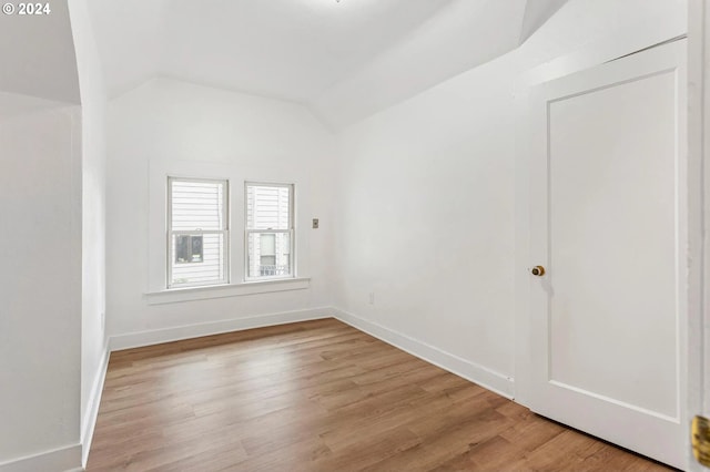 spare room featuring lofted ceiling and light wood-type flooring