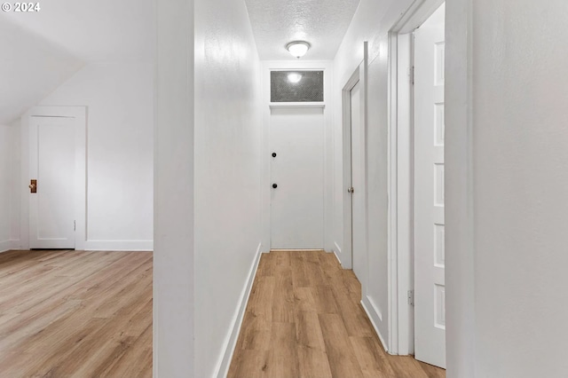 hall with a textured ceiling and light wood-type flooring