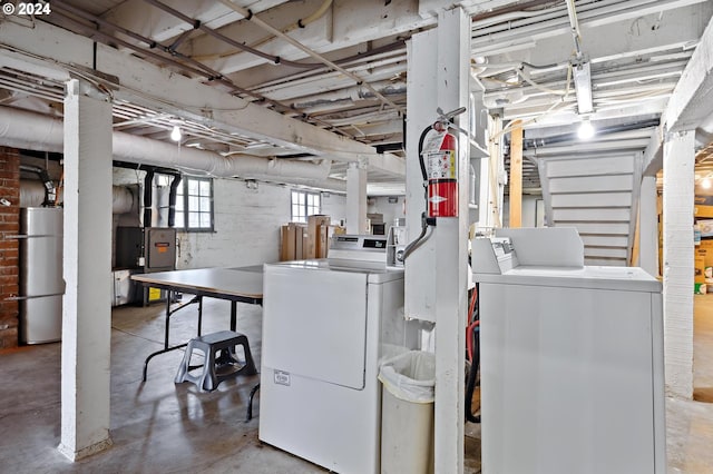 laundry room with water heater, brick wall, and washer and clothes dryer