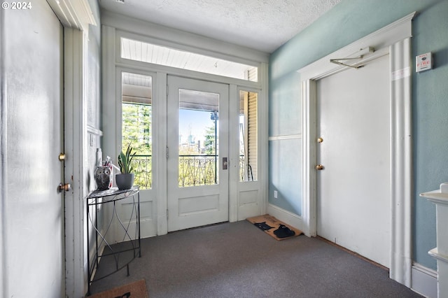 entryway with a textured ceiling and dark colored carpet