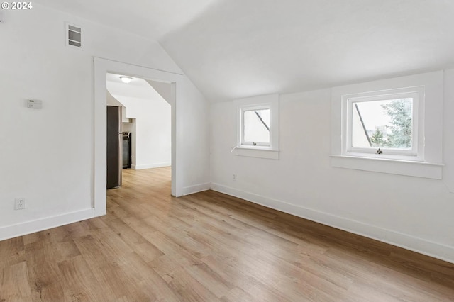 empty room with lofted ceiling and light hardwood / wood-style flooring