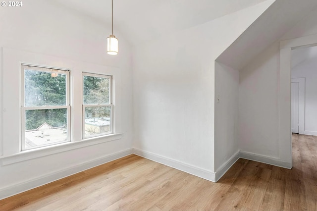 spare room featuring lofted ceiling and light wood-type flooring