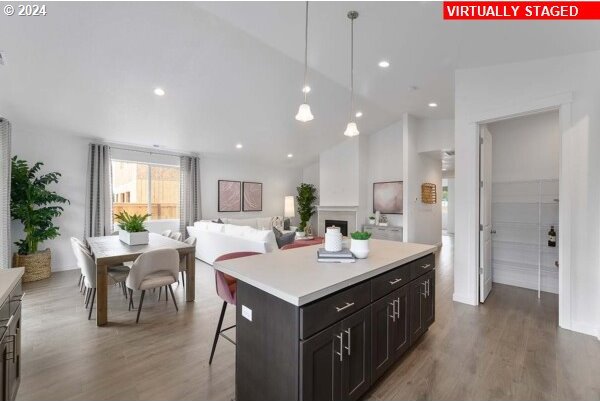 kitchen with a breakfast bar area, hanging light fixtures, a kitchen island, high vaulted ceiling, and hardwood / wood-style floors