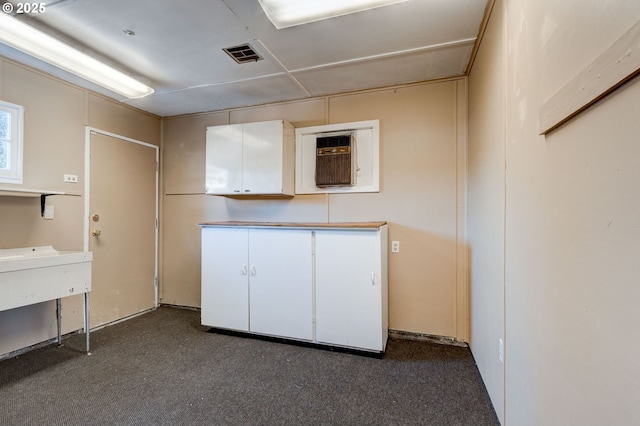 interior space featuring cabinets and dark carpet