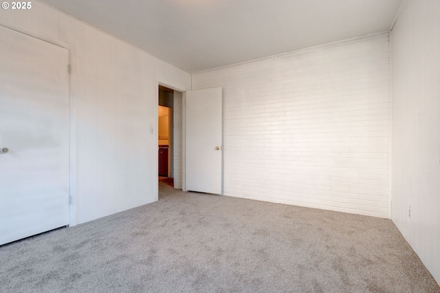 carpeted spare room with brick wall