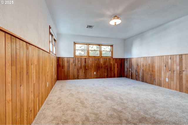 carpeted spare room with wood walls