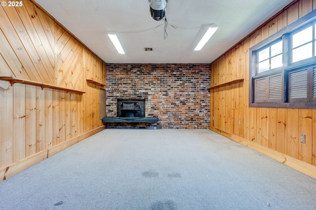 unfurnished living room featuring carpet floors, wood walls, and a wood stove