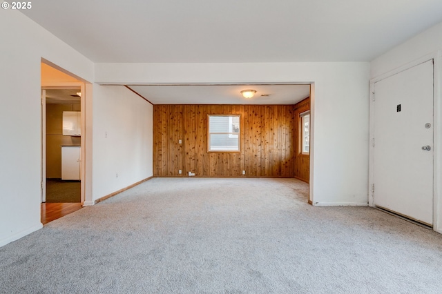 carpeted empty room featuring wooden walls