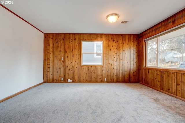 carpeted spare room featuring wood walls