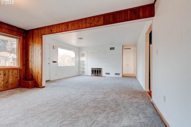 unfurnished living room with wooden walls, a fireplace, and carpet