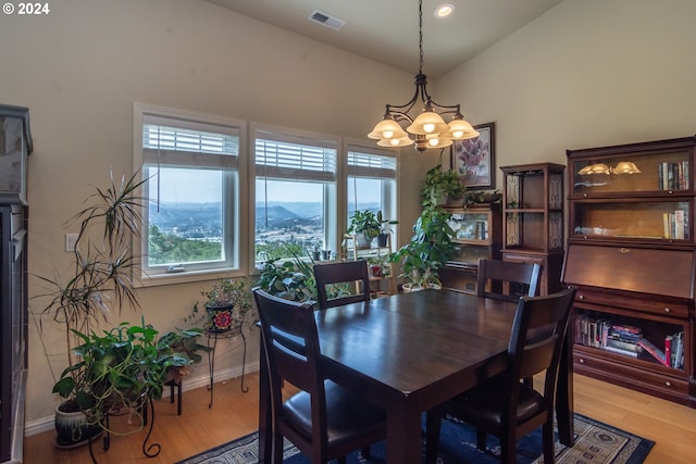 dining room with visible vents, baseboards, lofted ceiling, light wood-style floors, and a chandelier