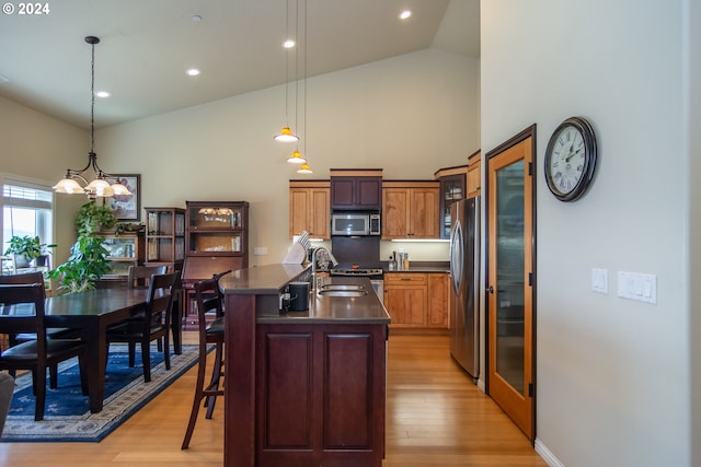 kitchen with dark countertops, light wood-style floors, appliances with stainless steel finishes, and a sink