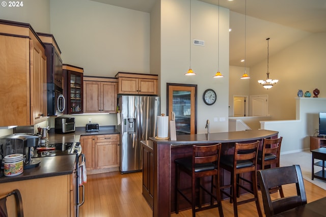 kitchen featuring visible vents, high vaulted ceiling, stainless steel appliances, dark countertops, and a kitchen breakfast bar