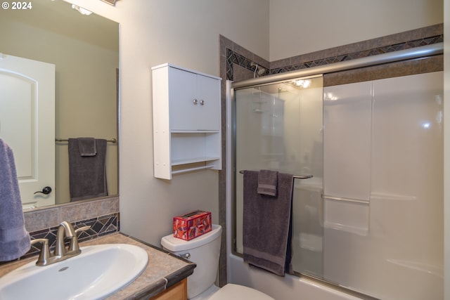 bathroom featuring decorative backsplash, toilet, vanity, and shower / bath combination with glass door