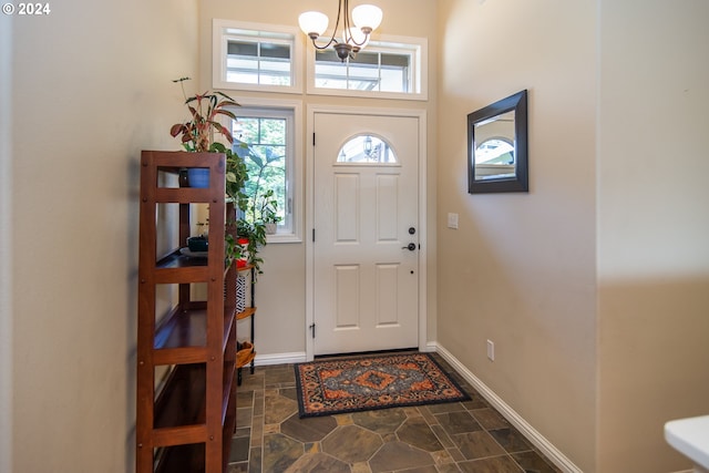 entryway with an inviting chandelier, baseboards, and stone finish flooring