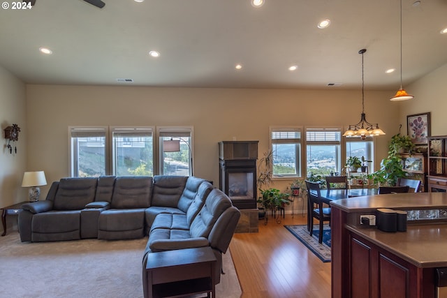 living room with a glass covered fireplace, an inviting chandelier, recessed lighting, and visible vents