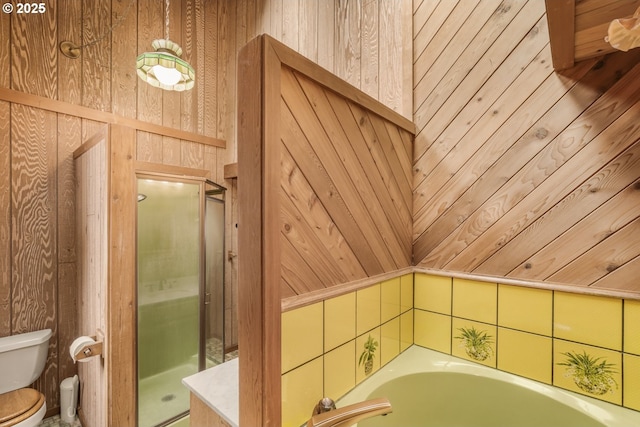 bathroom featuring a garden tub, wooden walls, toilet, and a shower stall