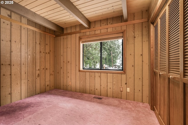 carpeted spare room with wooden ceiling, beam ceiling, and wood walls