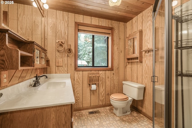 bathroom featuring toilet, a shower with shower door, wood walls, wooden ceiling, and vanity