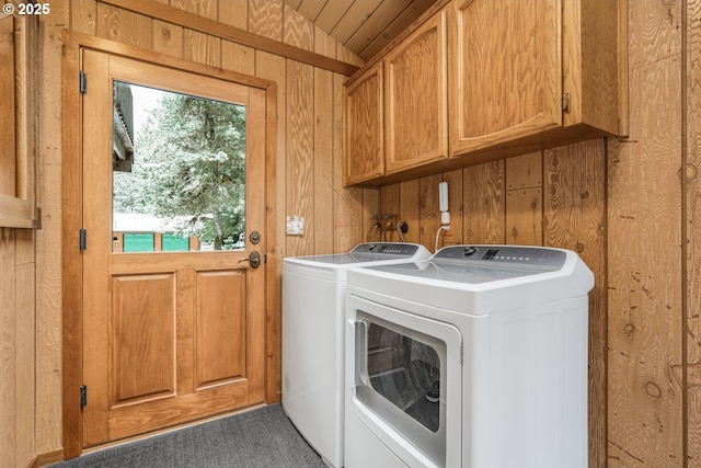 laundry area with cabinet space, a healthy amount of sunlight, wood walls, and separate washer and dryer