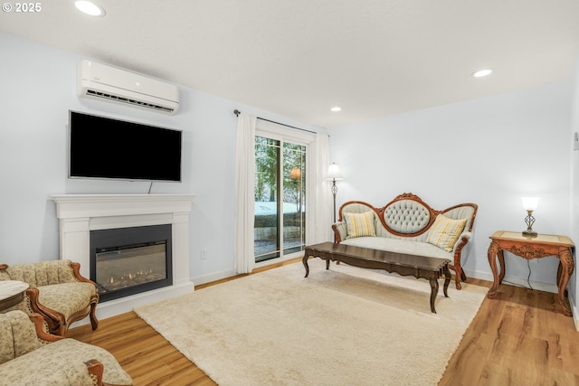 interior space with a glass covered fireplace, wood finished floors, recessed lighting, and a wall unit AC