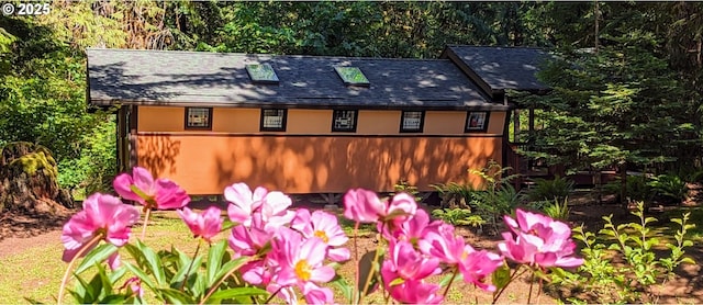 exterior space with stucco siding and roof with shingles