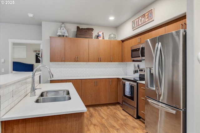 kitchen featuring kitchen peninsula, appliances with stainless steel finishes, light wood-type flooring, backsplash, and sink