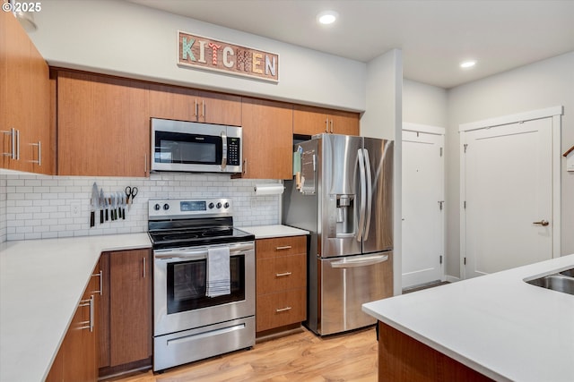 kitchen with backsplash, light hardwood / wood-style flooring, stainless steel appliances, and sink