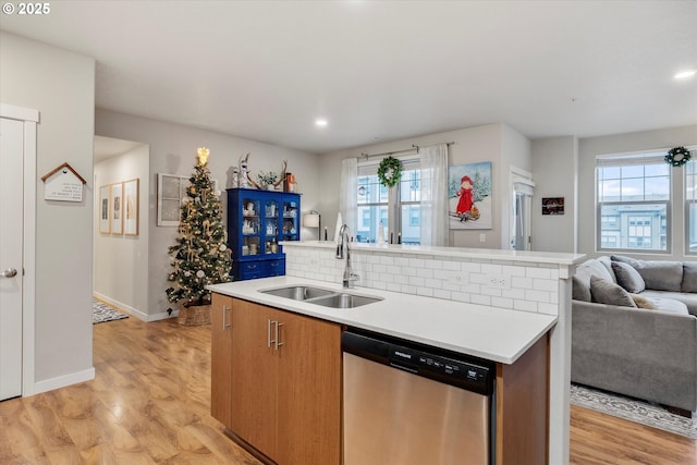 kitchen with light wood-type flooring, a healthy amount of sunlight, sink, a center island with sink, and dishwasher