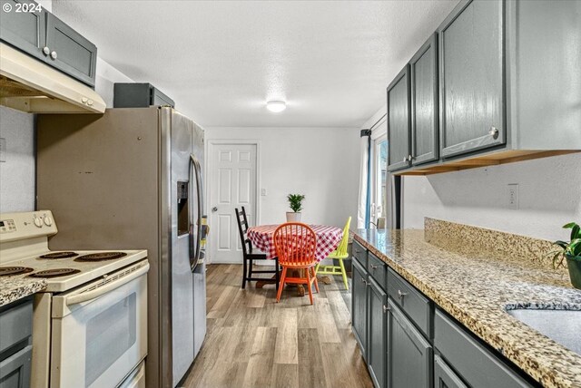 kitchen featuring white electric range, gray cabinets, light stone countertops, light hardwood / wood-style floors, and extractor fan